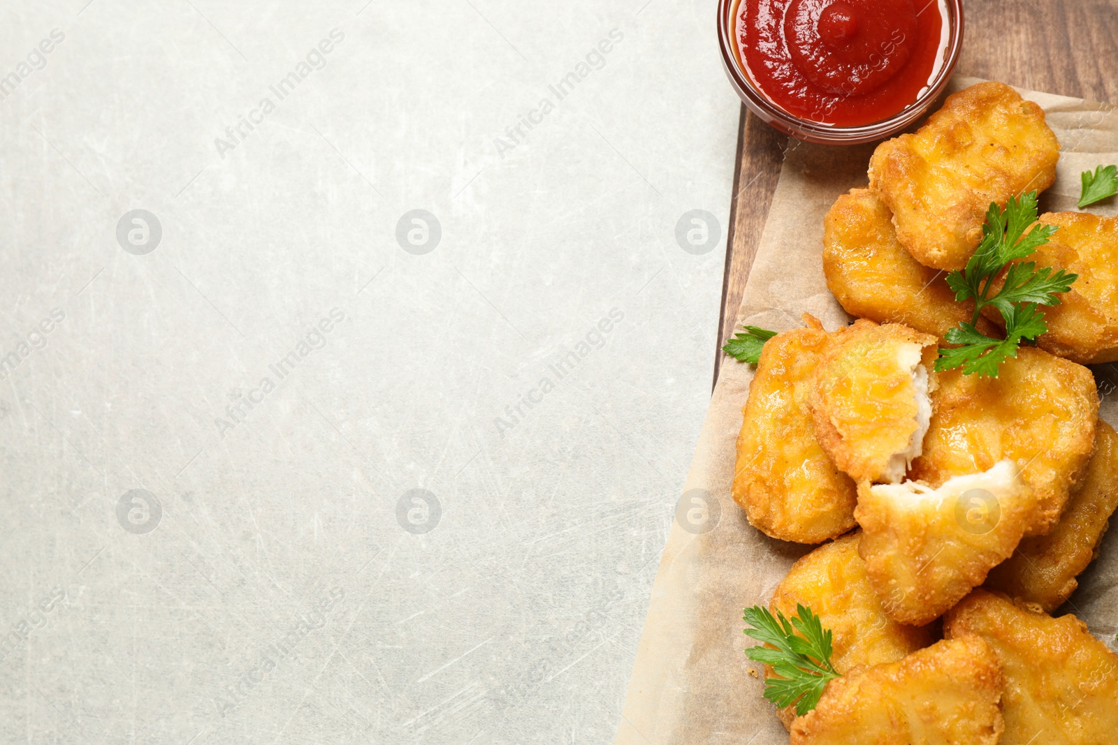 Photo of Tasty fried chicken nuggets on light grey table, top view. Space for text