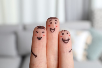 Three fingers with drawings of happy faces on blurred background