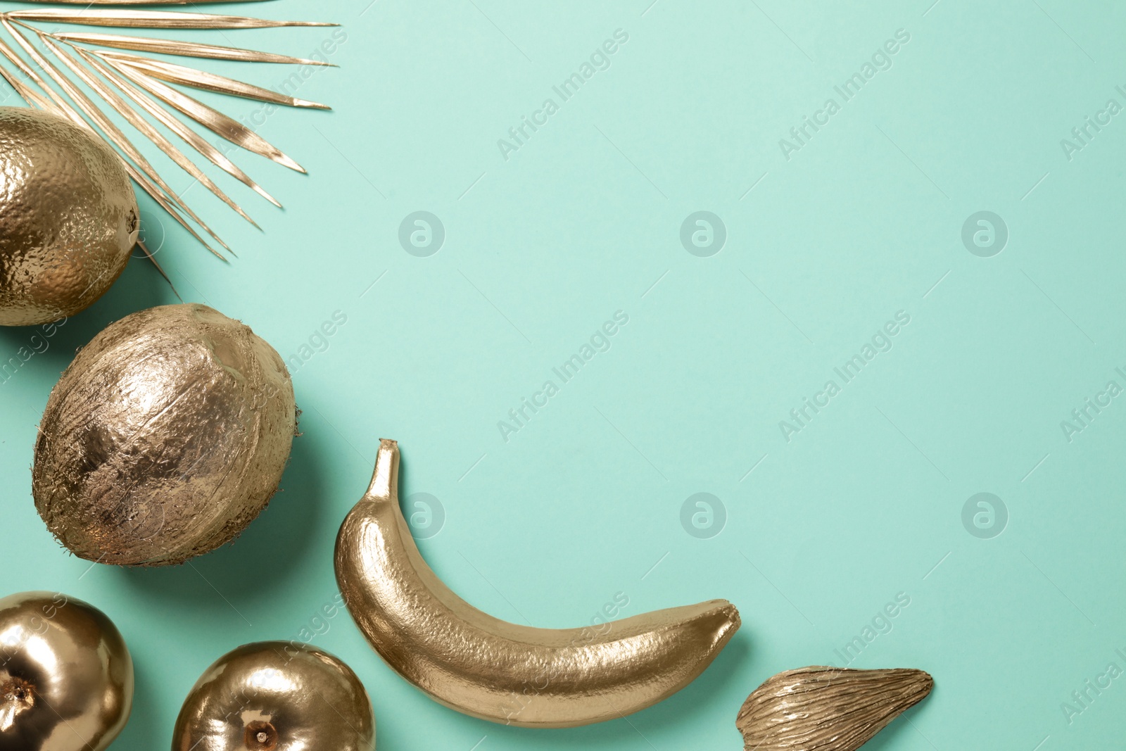 Photo of Different golden fruits and palm leaf on turquoise background, flat lay. Space for text