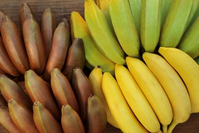 Different sorts of bananas on wooden table, top view
