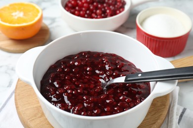Photo of Fresh cranberry sauce in bowl served on table, closeup