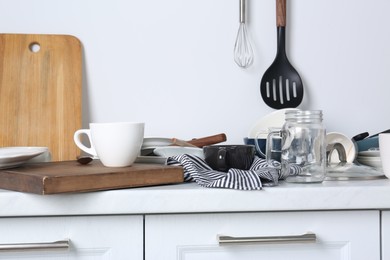 Many dirty utensils and dishware on countertop in messy kitchen