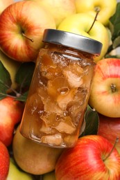 Photo of Delicious apple jam in jar on fresh fruits, top view