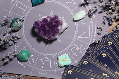 Photo of Astrology prediction. Zodiac wheel, gemstones, tarot cards and lavender on wooden table, flat lay