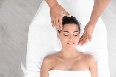 Relaxed woman receiving head massage in wellness center, top view