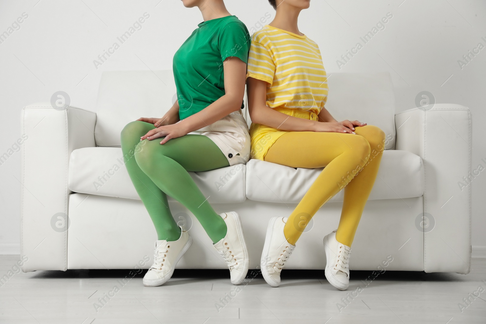 Photo of Women wearing bright tights sitting on sofa indoors, closeup