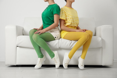 Photo of Women wearing bright tights sitting on sofa indoors, closeup