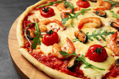 Photo of Delicious seafood pizza on wooden board, closeup