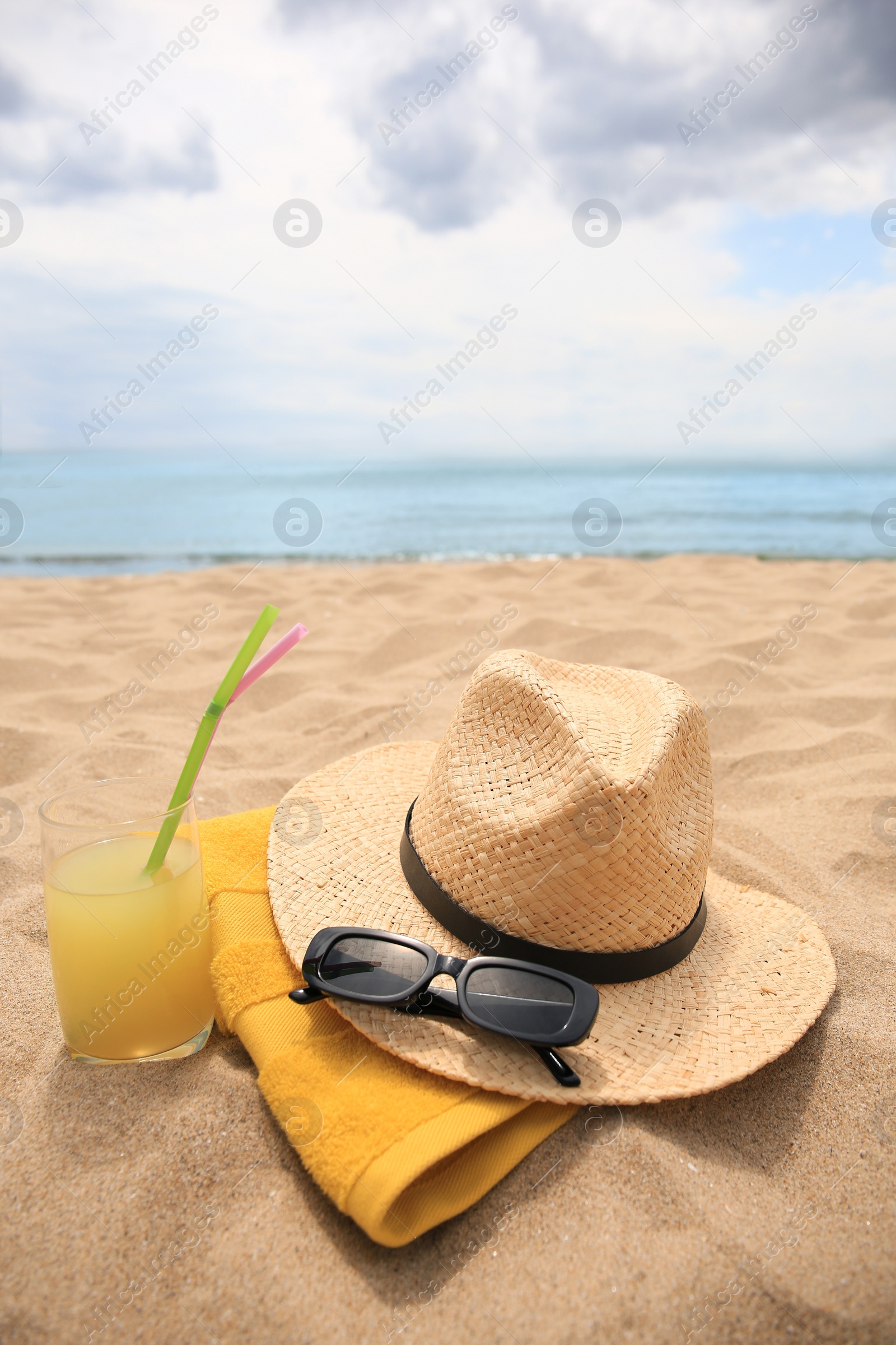 Photo of Straw hat, sunglasses, towel and refreshing drink on sandy beach near sea. Space for text