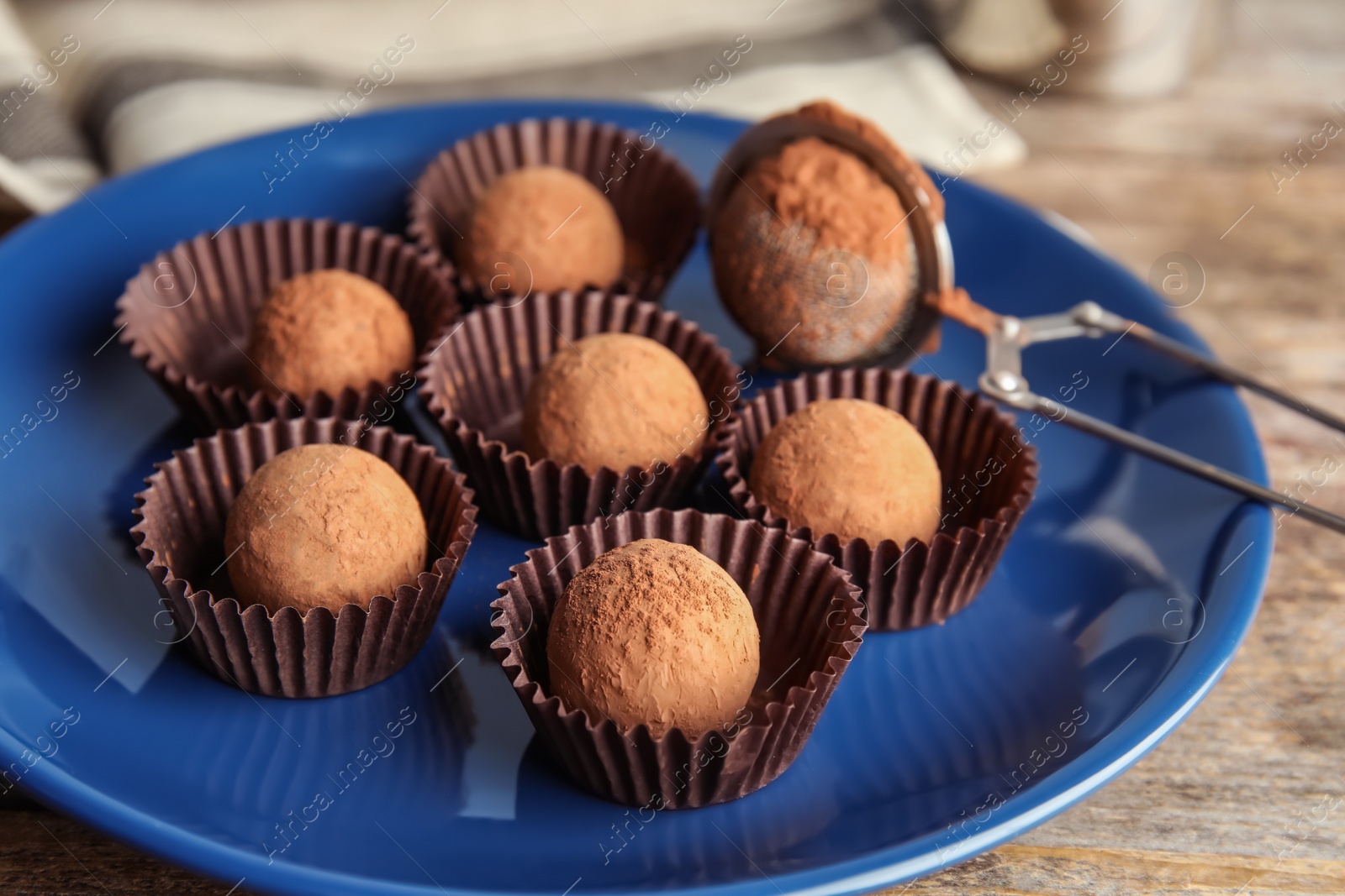 Photo of Plate with chocolate truffles on wooden background