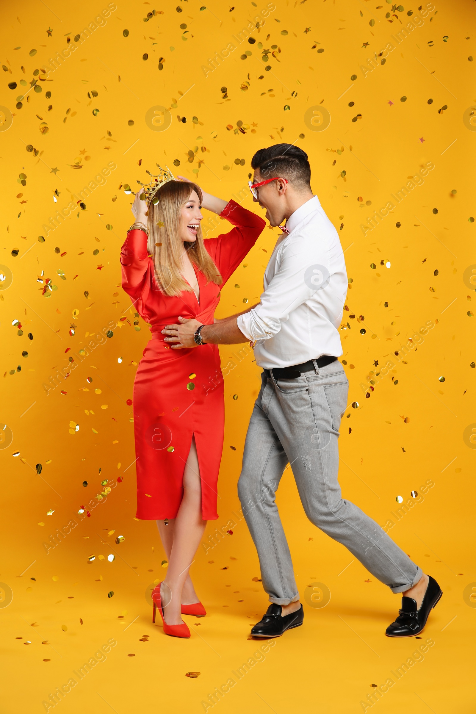 Photo of Happy couple and confetti on yellow background