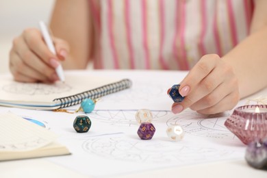 Photo of Astrologer using dice for fate forecast at table, closeup. Fortune telling