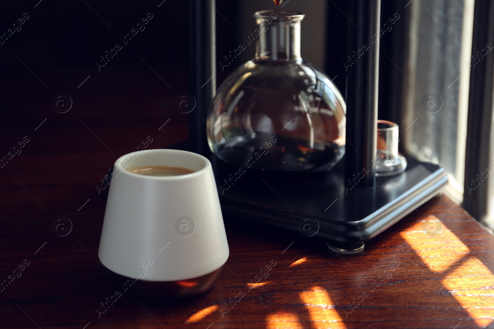 Photo of Cup with coffee and vacuum maker on wooden table in cafe