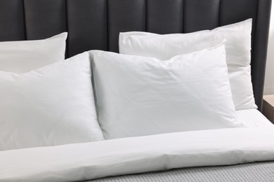 Photo of Soft white pillows and duvet on bed, closeup