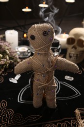 Photo of Voodoo doll with pins and dried flowers on table indoors