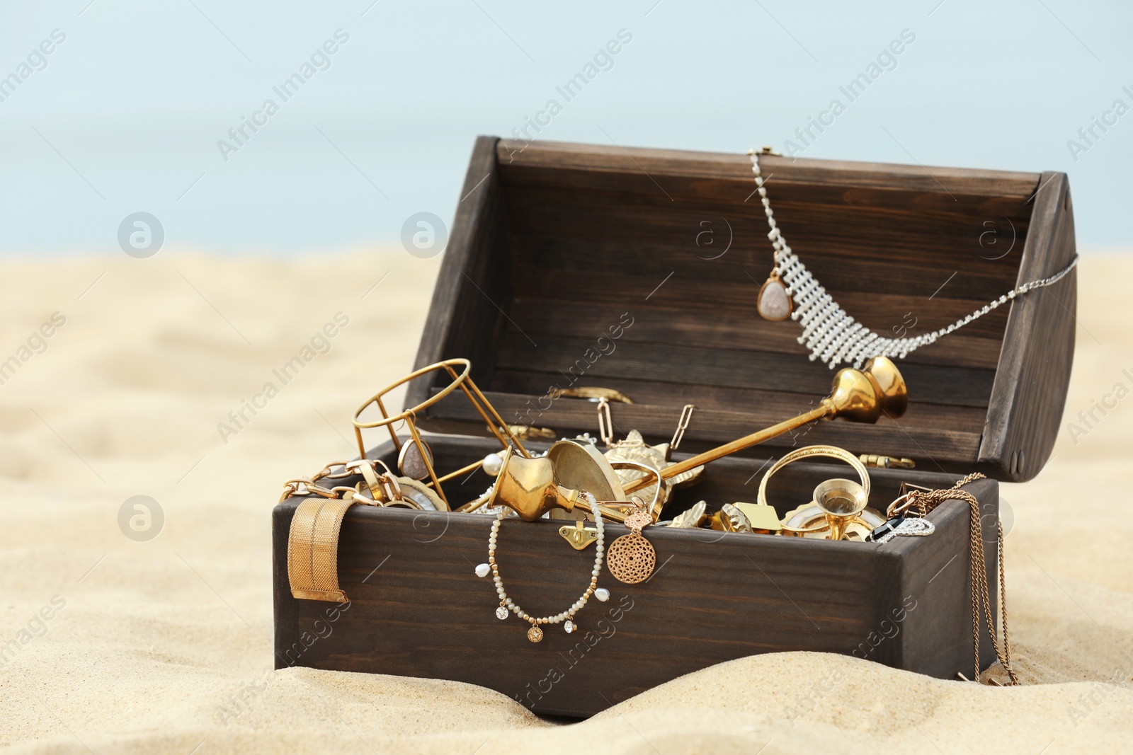 Photo of Open wooden treasure chest on sandy beach