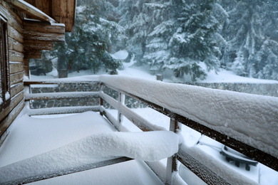 Photo of Cottage balcony covered with snow. Winter beauty