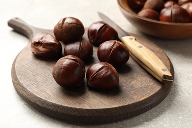 Photo of Fresh edible sweet chestnuts on grey table, closeup