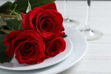 Photo of Beautiful place setting with dishware and roses for romantic dinner on white wooden table, closeup