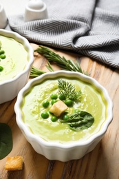 Photo of Fresh vegetable detox soup made of green peas and spinach with croutons served on table