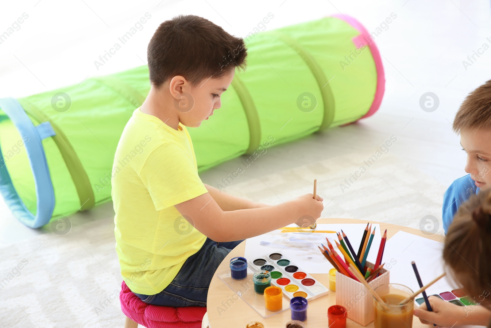 Photo of Cute little children painting at table in playing room