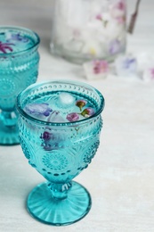 Photo of Glasses with floral ice cubes and water on table. Space for text