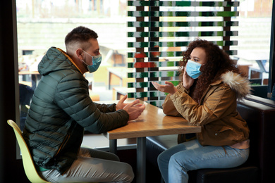 Photo of Couple with disposable masks in cafe. Virus protection