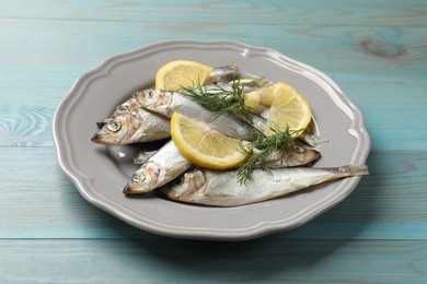 Fresh raw sprats, dill and cut lemon on light blue wooden table