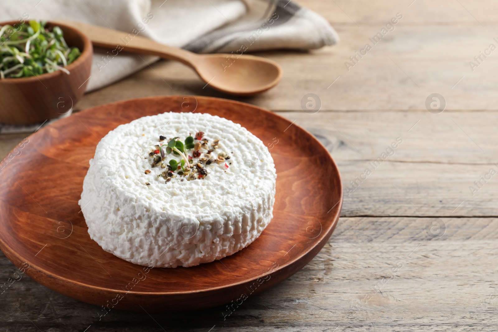 Photo of Plate of fresh cottage cheese with spice and microgreens on wooden table. Space for text