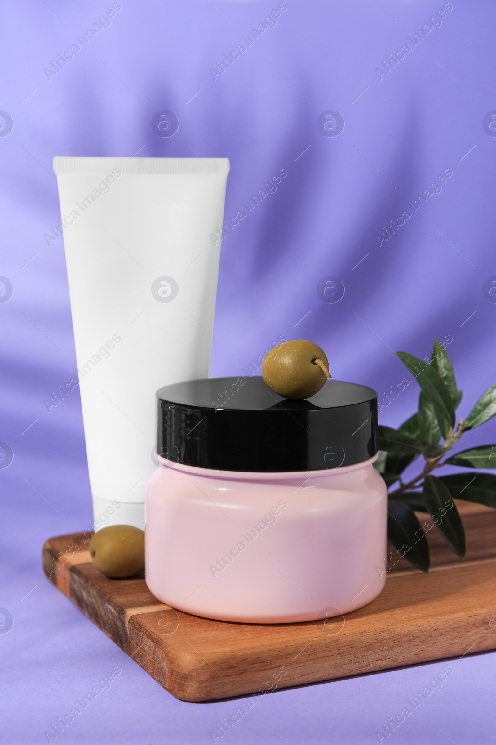 Photo of Cosmetic products and olives on lilac background