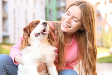 Photo of Young woman with adorable Cavalier King Charles Spaniel dog outdoors
