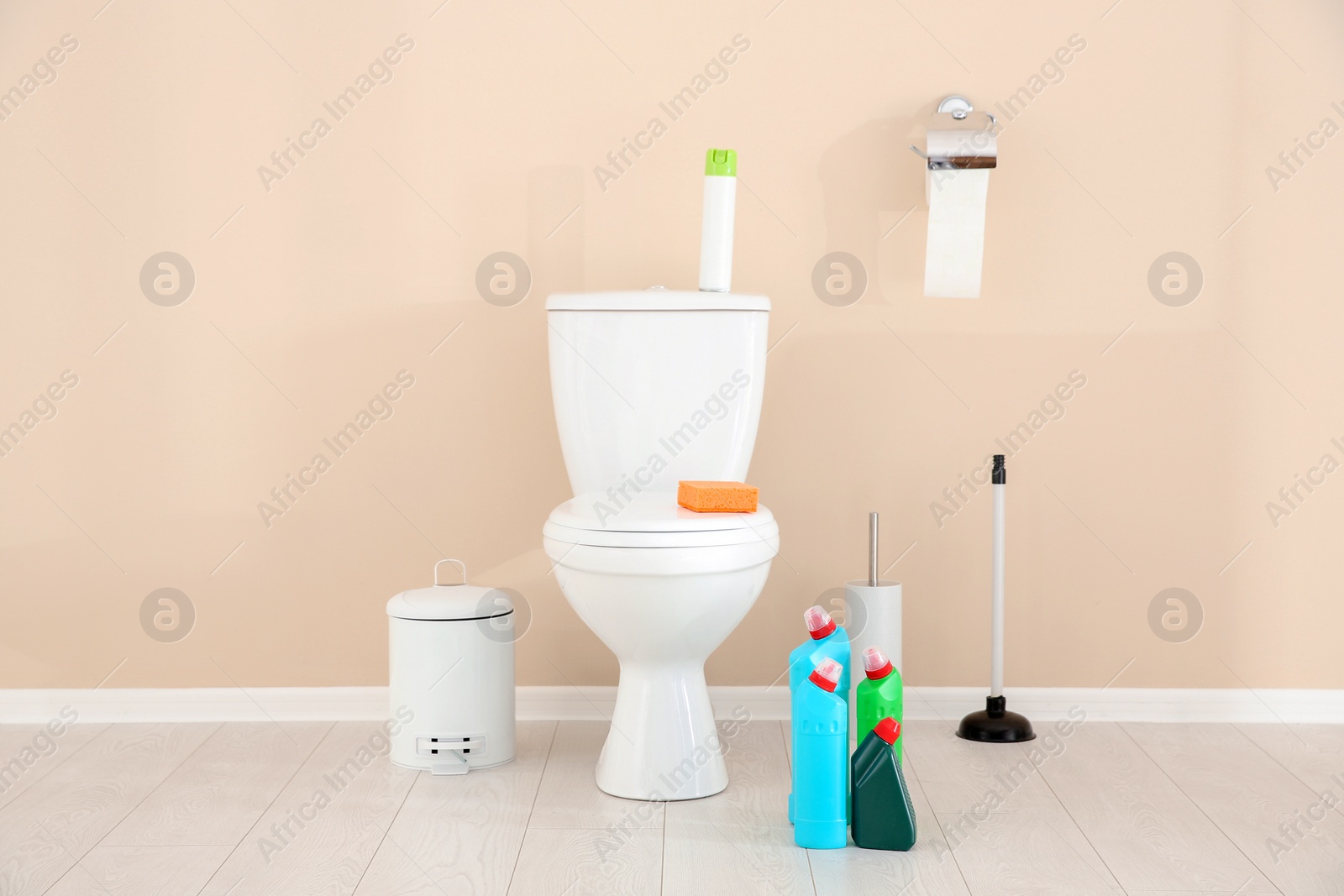 Photo of Ceramic toilet bowl, bottles of detergent and cleaning supplies in modern bathroom