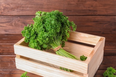 Photo of Crate with fresh green parsley on wooden table