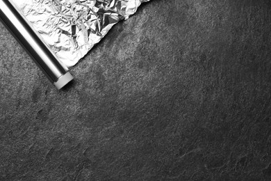 Roll of aluminum foil on grey table, top view. Space for text