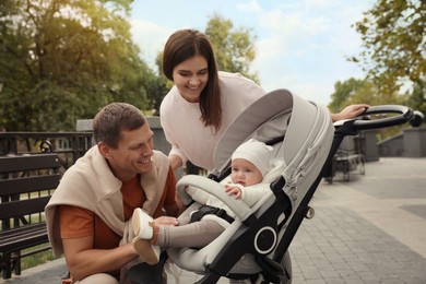 Happy parents walking with their adorable baby in stroller outdoors
