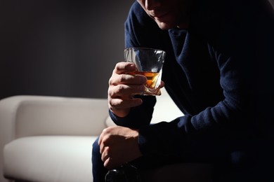 Photo of Addicted man with alcoholic drink on sofa indoors, closeup