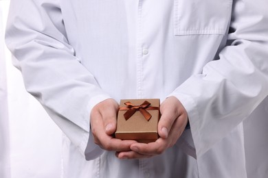 Photo of Doctor holding gift box on white background, closeup. Medical present
