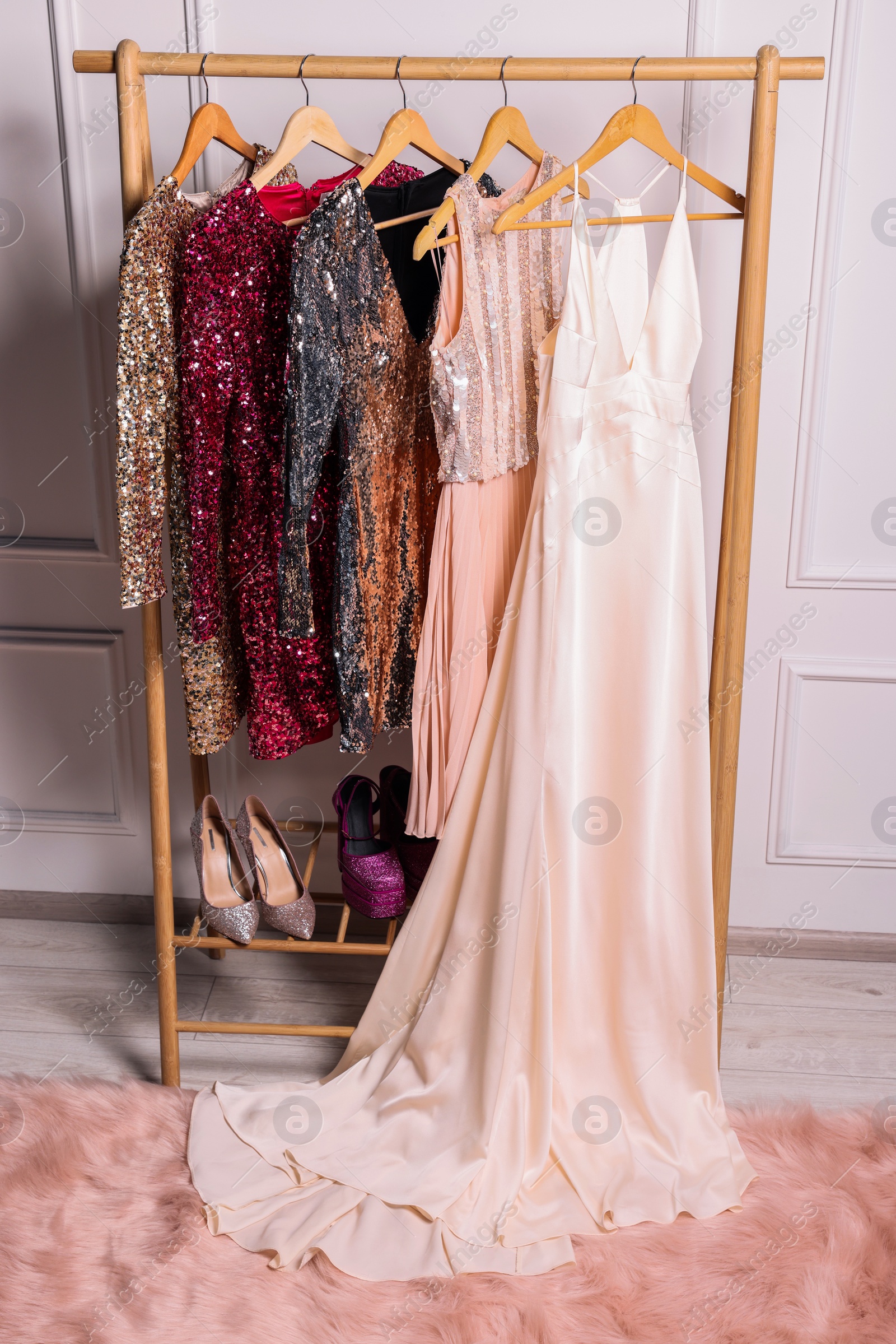 Photo of Rack with collection of stylish dresses and shoes in room. Preparing for party