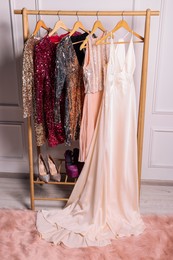 Rack with collection of stylish dresses and shoes in room. Preparing for party