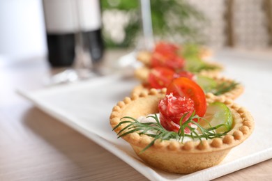 Delicious canapes with dry smoked sausages, cream cheese and vegetables on wooden table, closeup