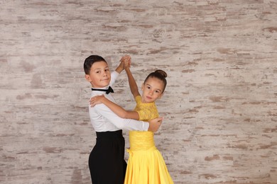 Beautifully dressed couple of kids dancing together in studio