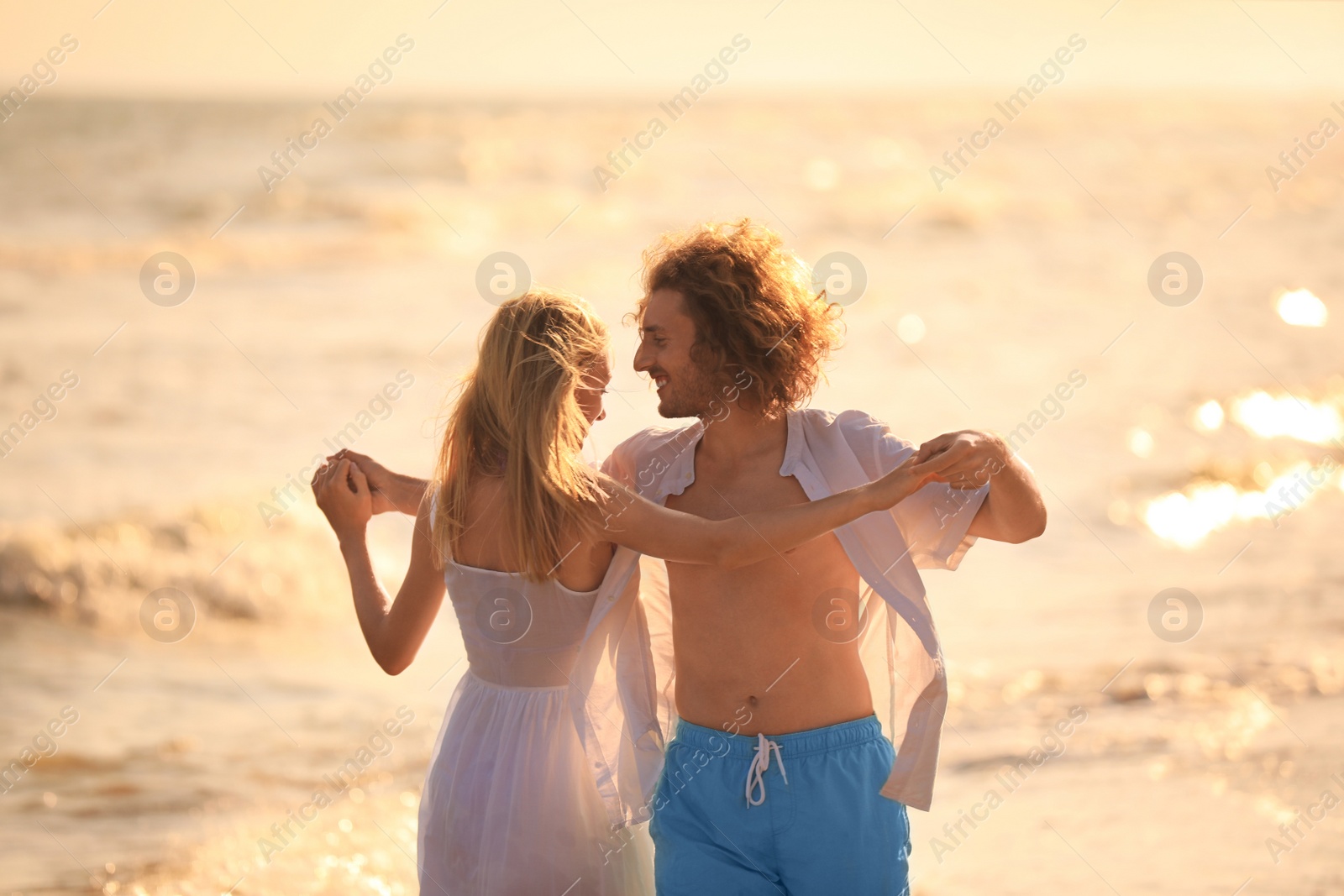 Photo of Young couple dancing on beach at sunset