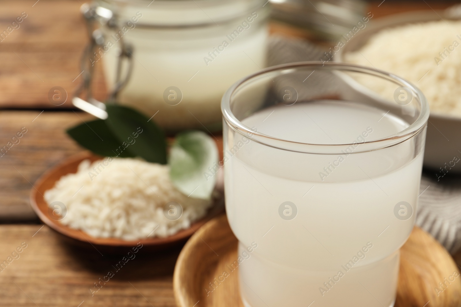 Photo of Glass of rice water on wooden table, closeup