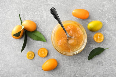 Delicious kumquat jam and fresh fruits on light grey table, flat lay