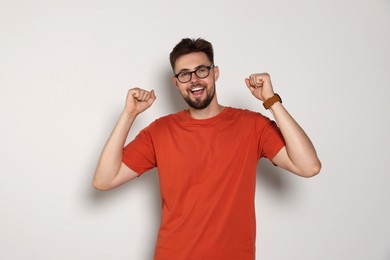 Photo of Handsome man in eyeglasses celebrating victory on light grey background