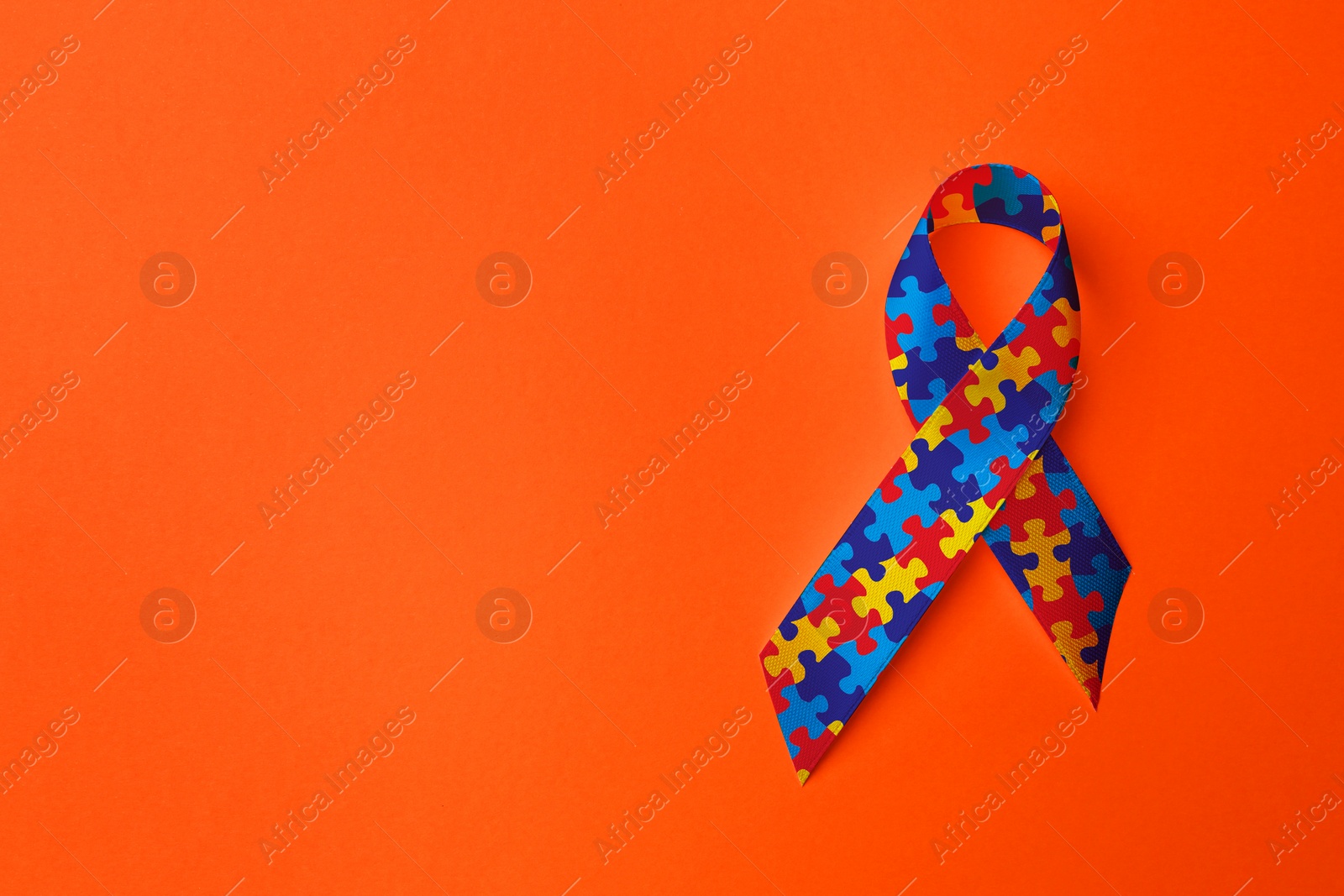 Image of World Autism Awareness Day. Colorful puzzle ribbon on orange background, top view with space for text