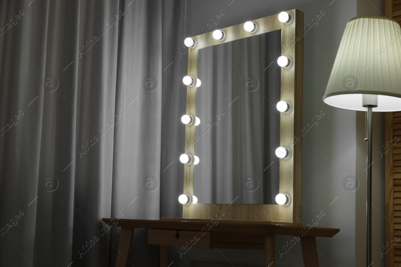 Photo of Beautiful mirror with light bulbs and lamp in makeup room