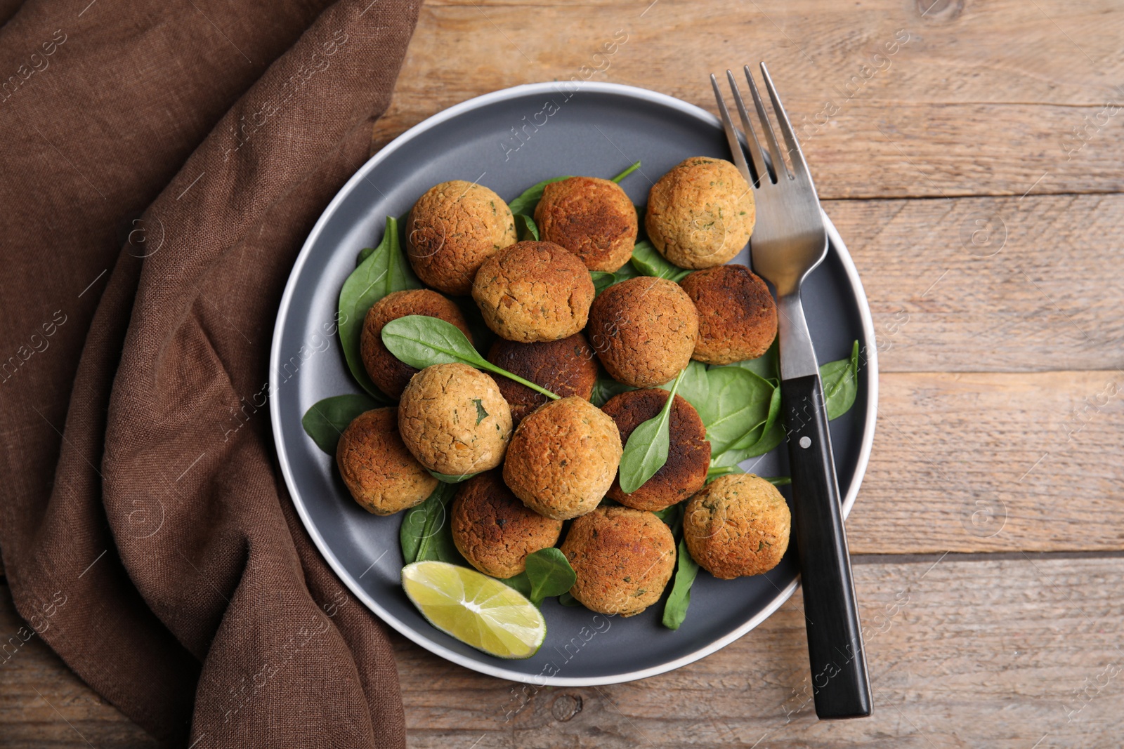 Photo of Delicious falafel balls with lime on wooden table, top view