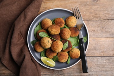 Delicious falafel balls with lime on wooden table, top view