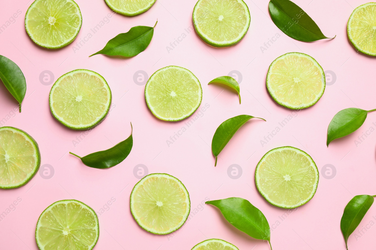 Photo of Juicy fresh lime slices and green leaves on pink background, flat lay